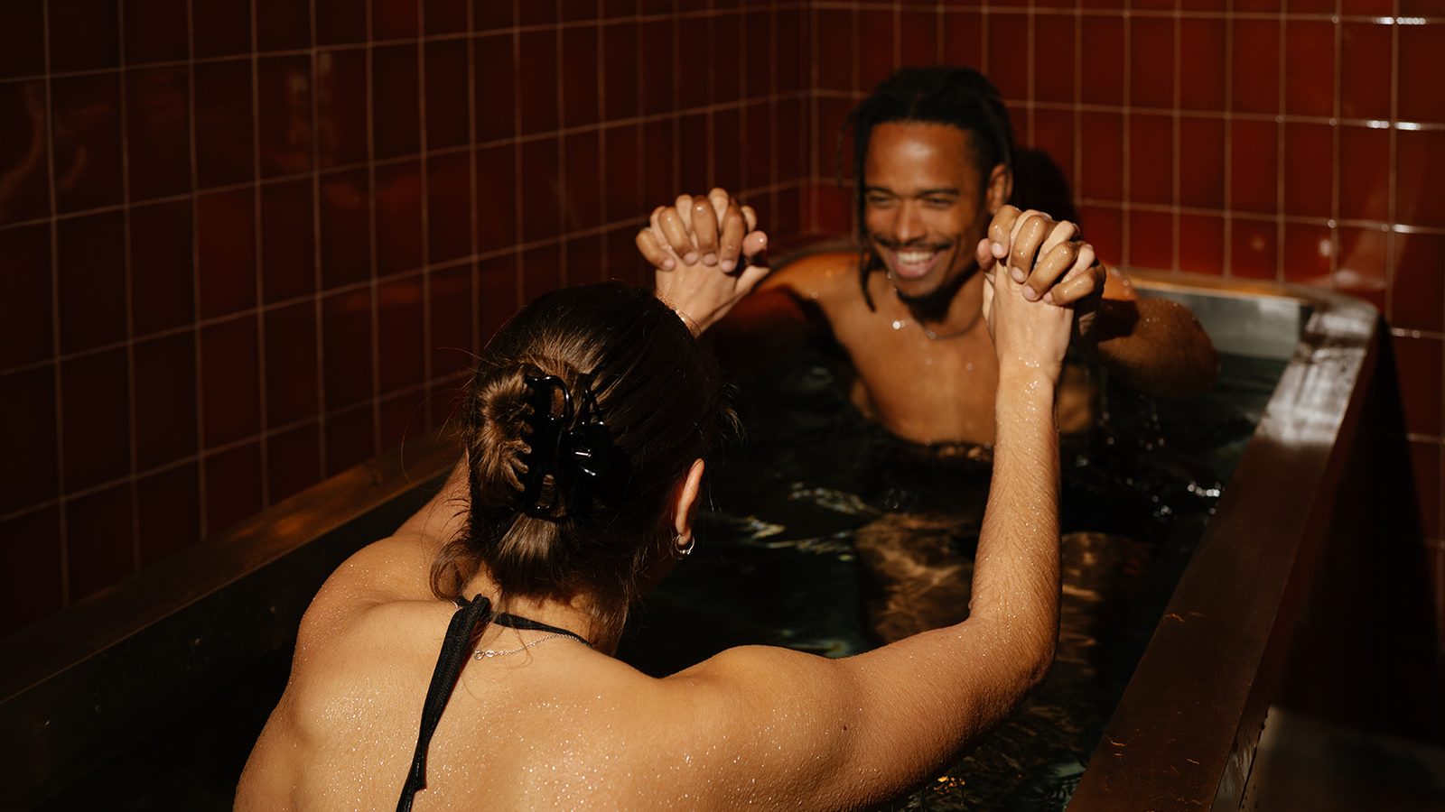 Two guests holding hands in an ice bath at ILO Studios, Barcelona